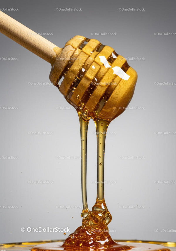 Golden honey flowing smoothly from wooden dipper