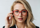 Elegant woman with blonde hair wearing red glasses in studio portrait