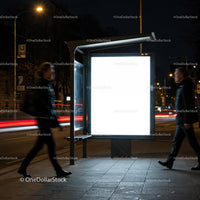 People Walking Past Illuminated Bus Stop Advertising at Night
