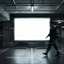 Blurred man walking past empty lighted billboard in parking garage