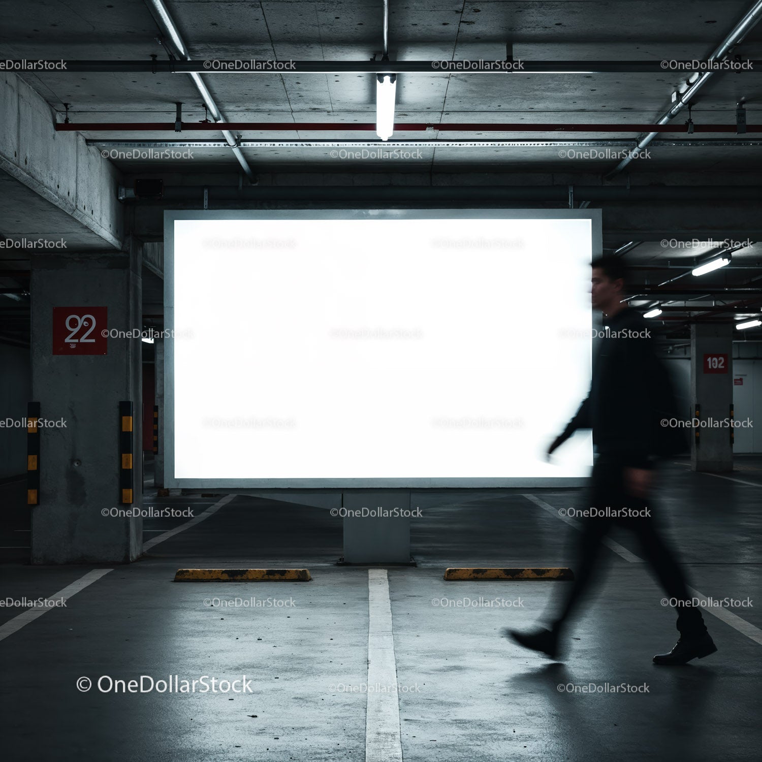 Blurred man walking past empty lighted billboard in parking garage