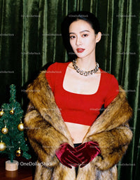 Elegant woman in red top and fur coat posing indoors
