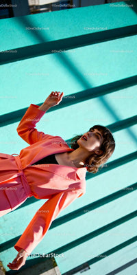 Stylish woman posing against turquoise wall outdoors