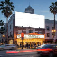 Historic theater marquee glowing at dusk in urban street
