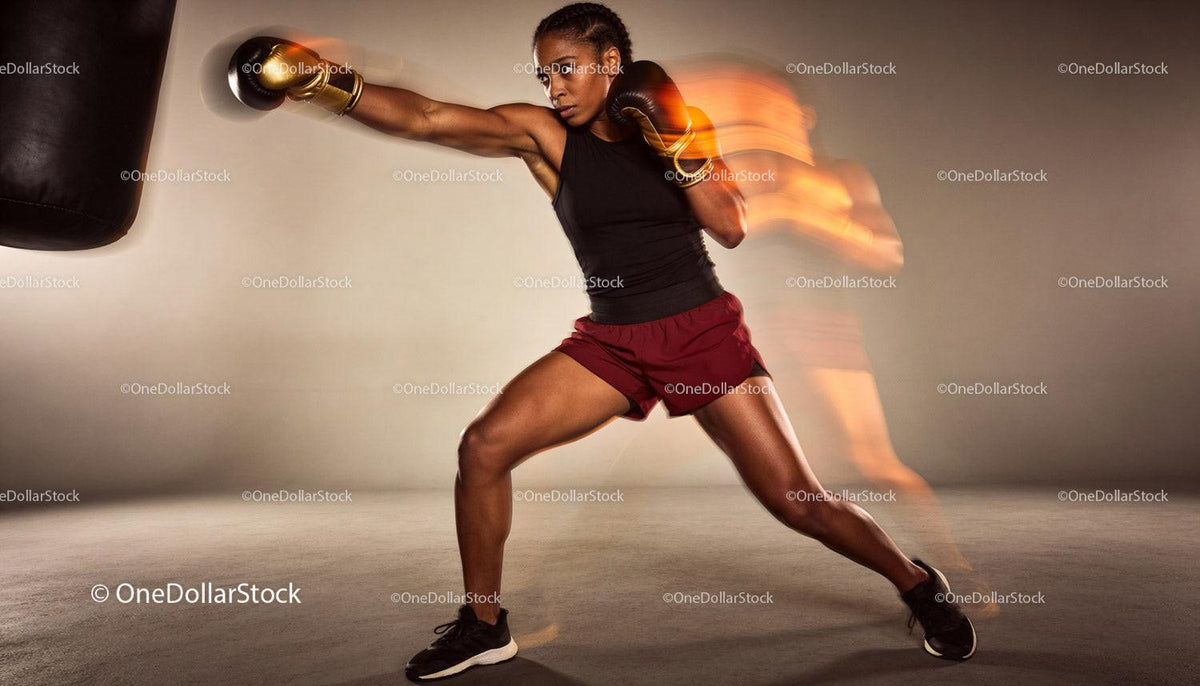 Focused woman boxer throwing powerful punch in gym