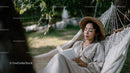 Tranquil Woman Relaxing in Hammock with Coffee in Beautiful Garden