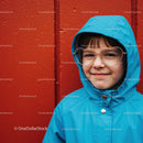Smiling child in blue raincoat with heart-shaped glasses