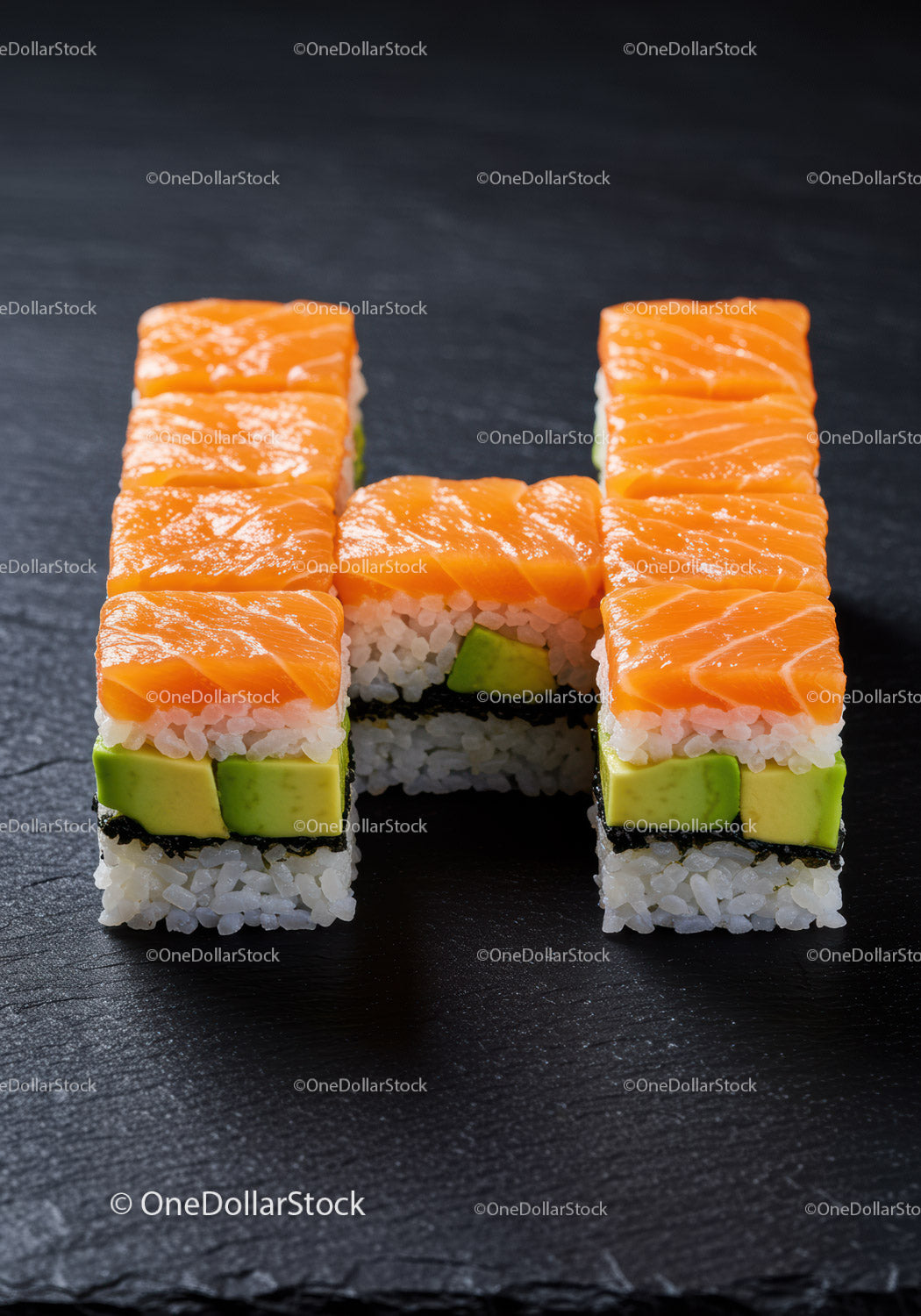 Sushi z łososiem i awokado w kształcie litery H na łupku