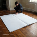 Person examining large blank pages on wooden floor