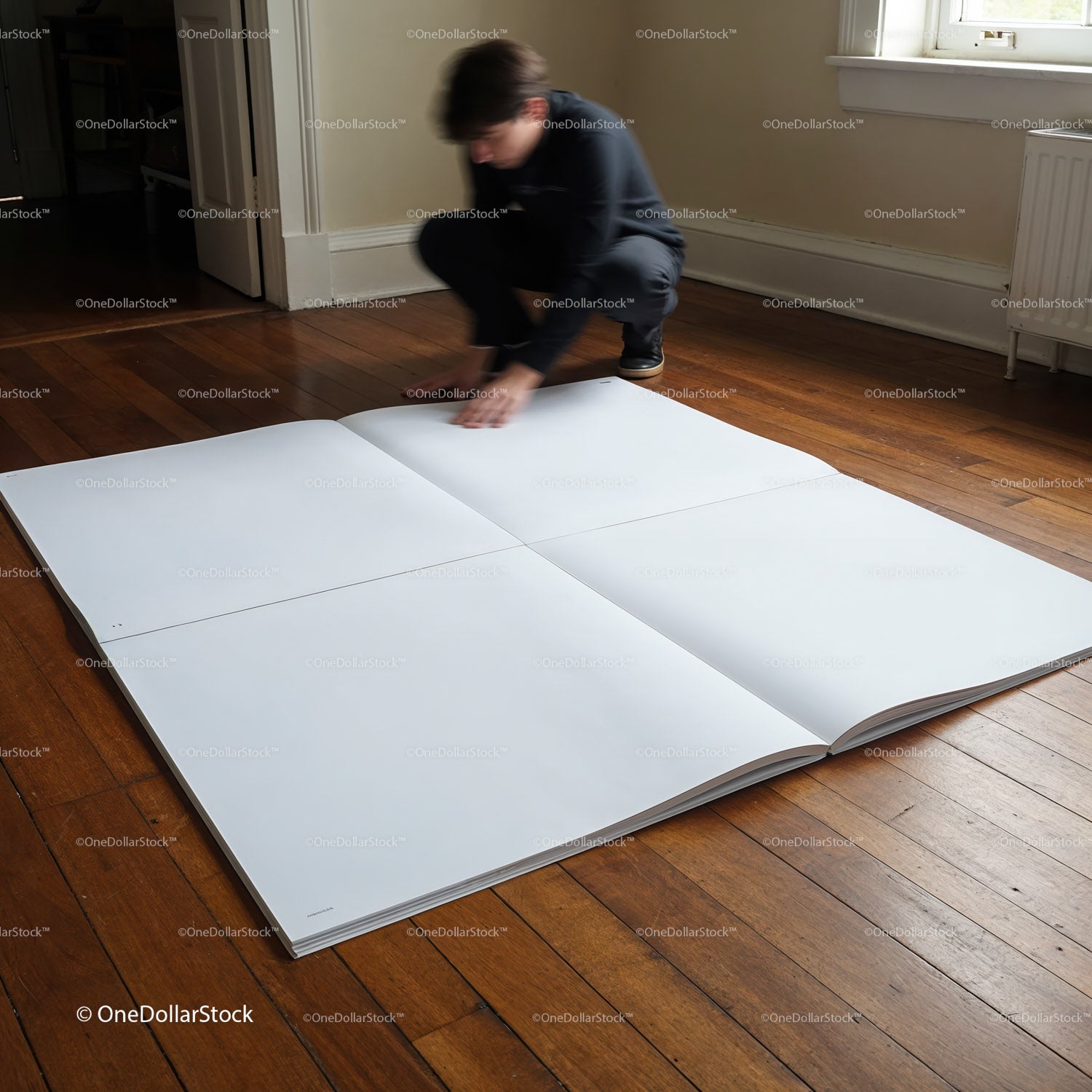 Person examining large blank pages on wooden floor