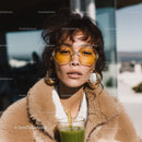 Stylish Woman Wearing Yellow Sunglasses Sitting Outdoors During Daylight