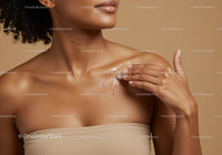 Close-up of a woman applying moisturizer with glowing skin and elegant pose