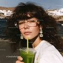 Stylish Woman Sipping Green Juice on Beach in Sunlit Summer Scene