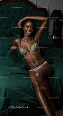 Smiling woman relaxing on green bed in lace lingerie