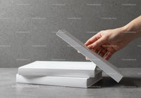 Hand Picking a Book from a Stack on Gray Surface