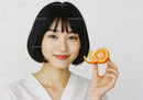 Young Woman Holding Fresh Orange Citrus Fruit in Bright Background