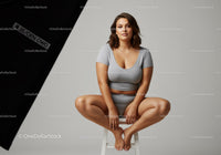 Young Woman Sitting on Stool in Casual Grey Outfit with Confident Expression