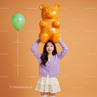 Smiling woman holding large gummy bear toy above head
