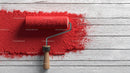 Red Paint Roller Spreading Bright Red Paint Over Rustic White Wooden Surface