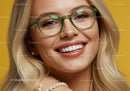 Smiling woman wearing green glasses and pearl accessories