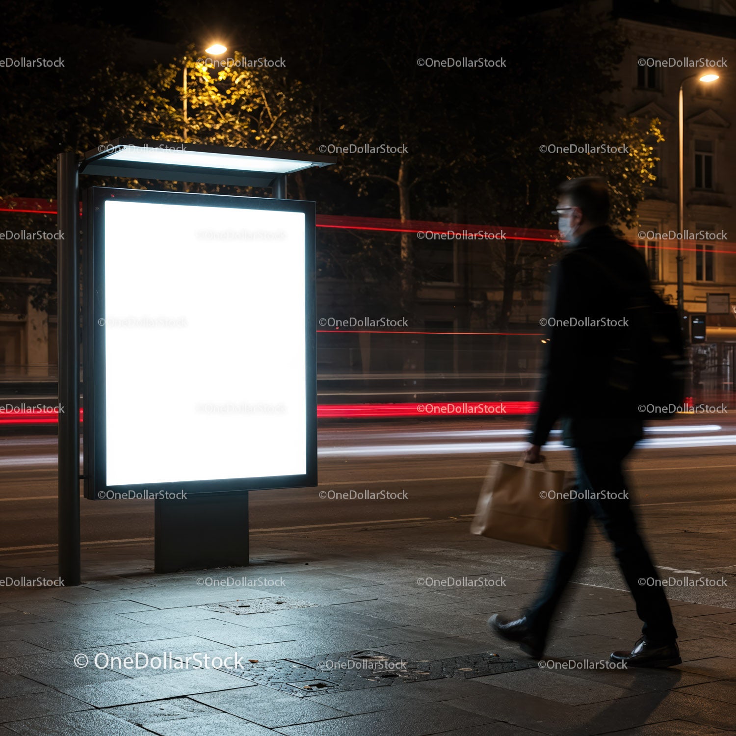 Mężczyzna przechodzący nocą obok oświetlonego, pustego billboardu miejskiego