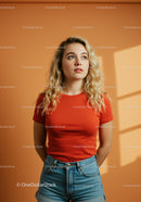 Thoughtful young woman in red shirt by sunny wall