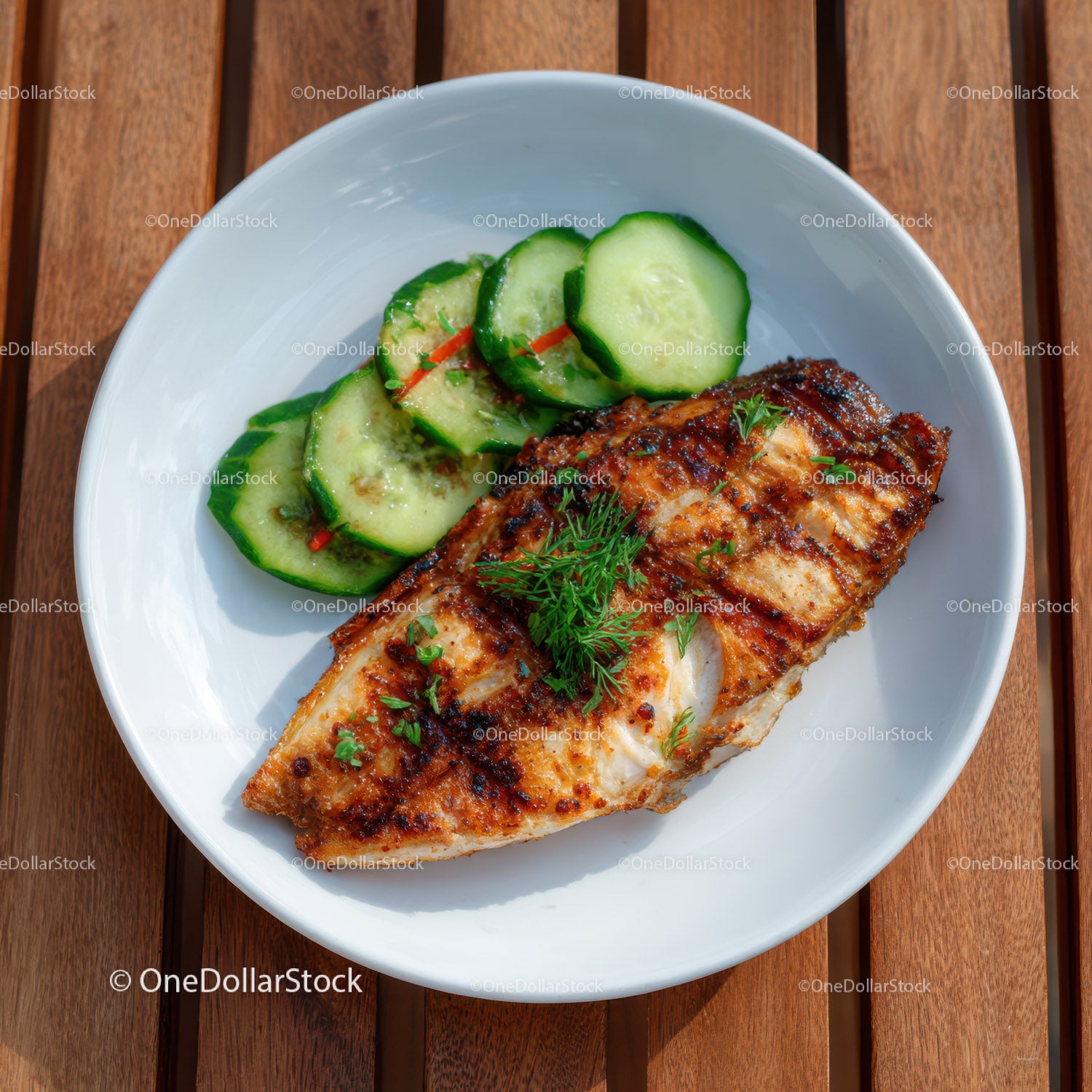 Grilled Fish with Cucumber Slices and Fresh Herbs on White Plate