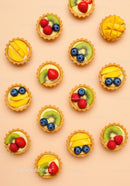 Assorted Mini Fruit Tarts on Peach Background