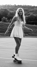 Young woman roller skating outdoors in summer dress