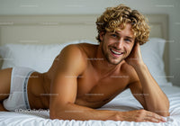 Smiling young man relaxing on bed in bright room