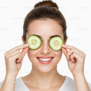 Smiling Woman Holding Cucumber Slices Over Eyes for Skincare and Relaxation