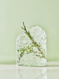 Ice Cube with Green Herb Inside on Light Green Background