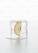 Green apple slice frozen inside melting ice cube