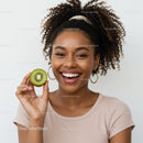 Bright Smiling Woman Holding Kiwi Slice in Fresh and Vibrant Portrait