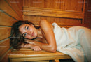 Relaxing Woman Lying on Wooden Sauna Bench in Warm Cozy Interior