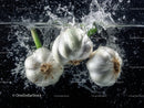 Fresh Garlic Bulbs Splashing into Water with Dynamic Motion