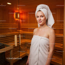Young Woman Relaxing in Sauna Wearing Towel in Warm Wooden Interior