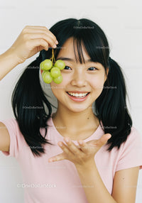 Smiling Girl Holding Green Grapes in Bright Indoor Setting