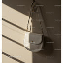 Minimalist white handbag hanging against beige wall