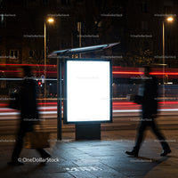 Illuminated Urban Bus Stop Sign at Night with Pedestrians