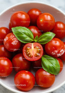 Fresh cherry tomatoes with basil leaves in white bowl