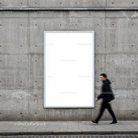 Blurred man walking past blank urban billboard on concrete wall