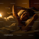 Woman Relaxing in Bed with Candles in a Cozy Atmosphere