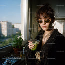 Stylish Young Woman with Sunglasses Enjoying Green Smoothie in Sunlit Apartment