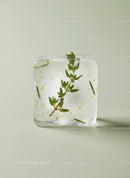 Herb and Gold Leaf in a Clear Ice Cube on Light Background