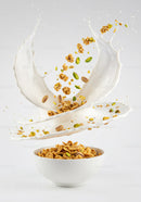 Cereal and pistachios splashing in milk bowl