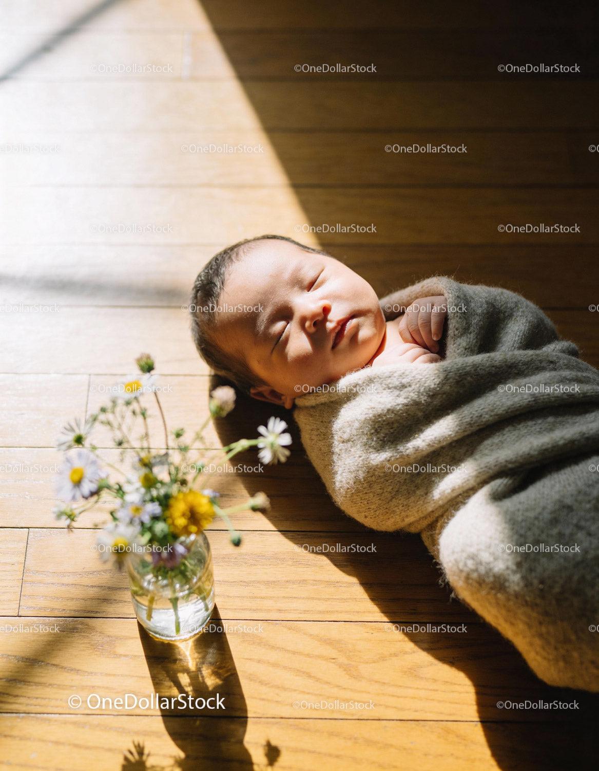 Peaceful newborn wrapped in cozy blanket on wooden floor