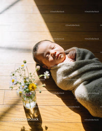 Peaceful newborn wrapped in cozy blanket on wooden floor