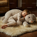 Little boy resting on giant plush bunny in cozy room