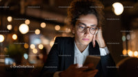 Focused Woman in Business Attire Using Smartphone in Night City Cafe